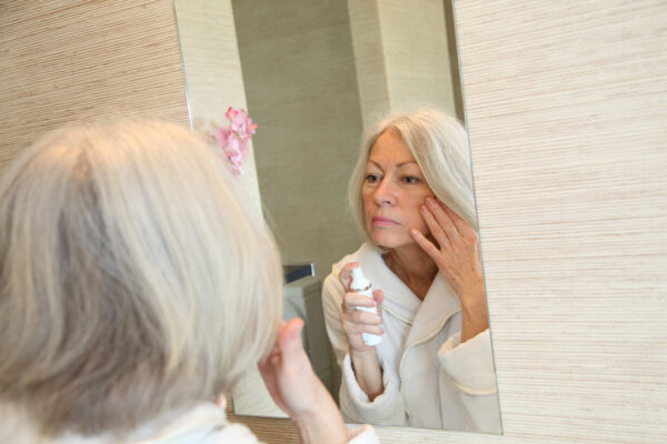 Senior-woman-applying-moisture-mirrors-skin